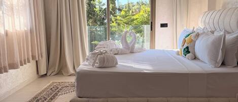 A spacious bedroom with a large bed, a patterned rug, and a view through a sliding glass door.