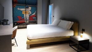 Ein modernes Hotelzimmer mit einem Bett, einem Schreibtisch und einem Wandbild von Astronauten.