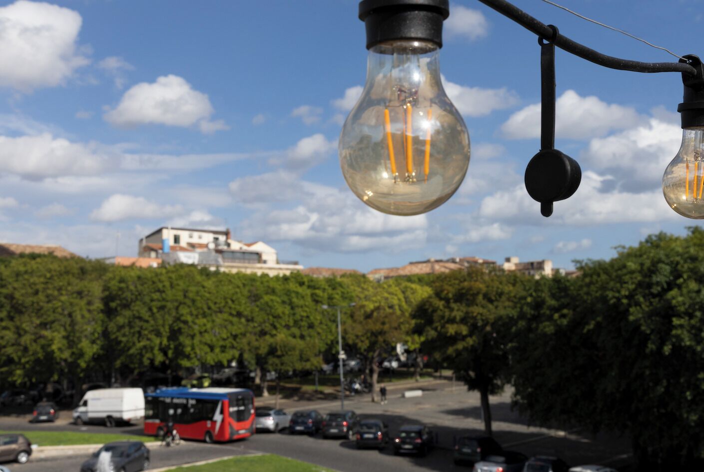 Une scène de rue avec un autobus, des voitures et des arbres.