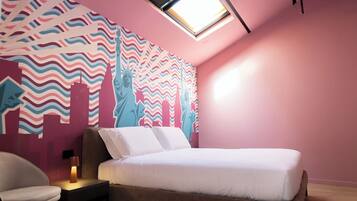 Un dormitorio con una cama, una silla, una mesita de noche y una pared con un mural de un paisaje urbano.