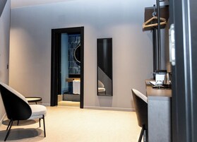 Una habitación de hotel moderna con diseño minimalista, que cuenta con un espejo grande, una zona de estar y una kitchenette.