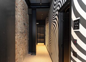 A hallway with a stone wall, a zebra-striped wall, and a door labeled '102'. - Made To Measure Catania Centro (Catania)