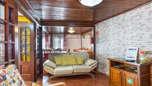 Um quarto com um sofá, um armário de madeira com o sinal de primeiros socorros, e uma parede de tijolos.