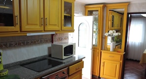 Une cuisine avec des meubles de couleur jaune, un four à micro-ondes, un évier et une fenêtre donnant sur l’extérieur.