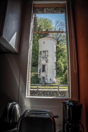 Une cuisine avec une fenêtre donnant sur un bâtiment blanc, de forme élancée, entouré de verdure.