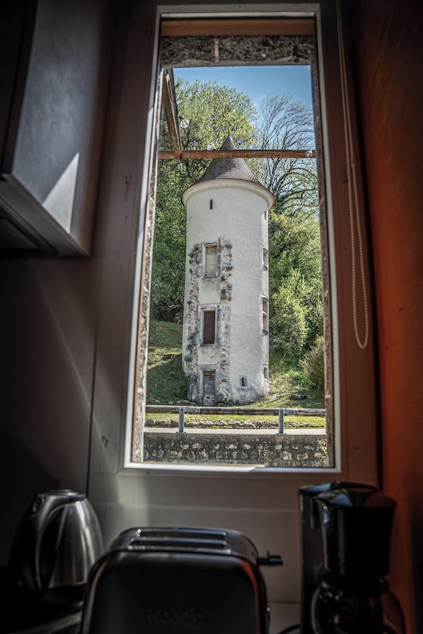 A kitchen with a window view of a white tower-like building surrounded by greenery.