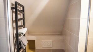 A compact bathroom with a toilet, a towel rack, a trash bin, and a shower door. - Studio 2 pers en Chartreuse - balcony, village center & nature | La Borne 31 (Saint-Pierre-d'Entremont)