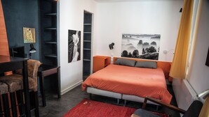 A bedroom with a bed, a desk, a chair, a bookshelf, and a large window. - Studio 2 pers en Chartreuse - balcony, village center & nature | La Borne 31 (Saint-Pierre-d'Entremont)