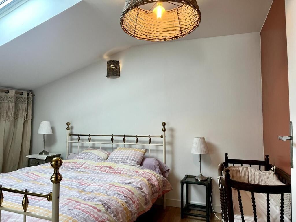 Ein Schlafzimmer mit Bett, Nachttischen, einer Hängelampe und einem Sessel.
