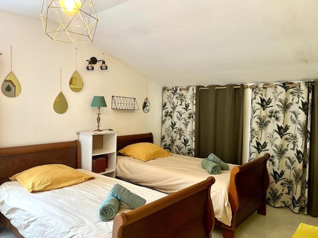Una habitación con dos camas, una lámpara, un estante y una luminaria de diseño geométrico.