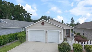 Una casa a un piano con garage, portico anteriore e staccionata.
