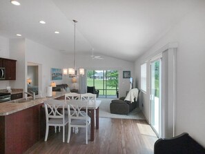 A modern kitchen with a dining area, large windows, and a view of the outdoors. - Meadow View - In The Villages (Wildwood)