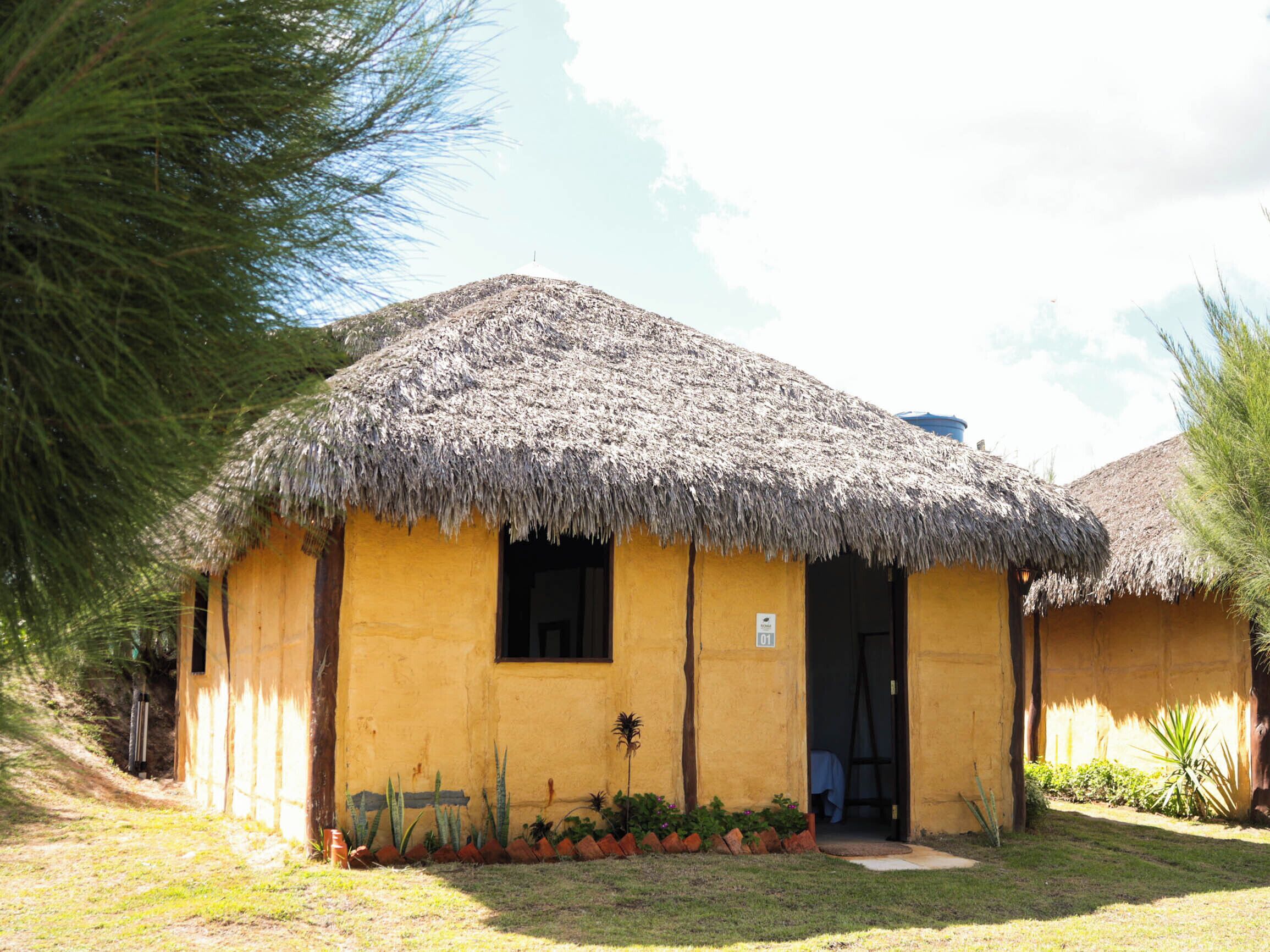 A single-story building with a thatched roof, a small window, and a door.