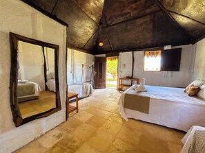 Een slaapkamer met een bed, nachtkastje, spiegel, raam en deur.