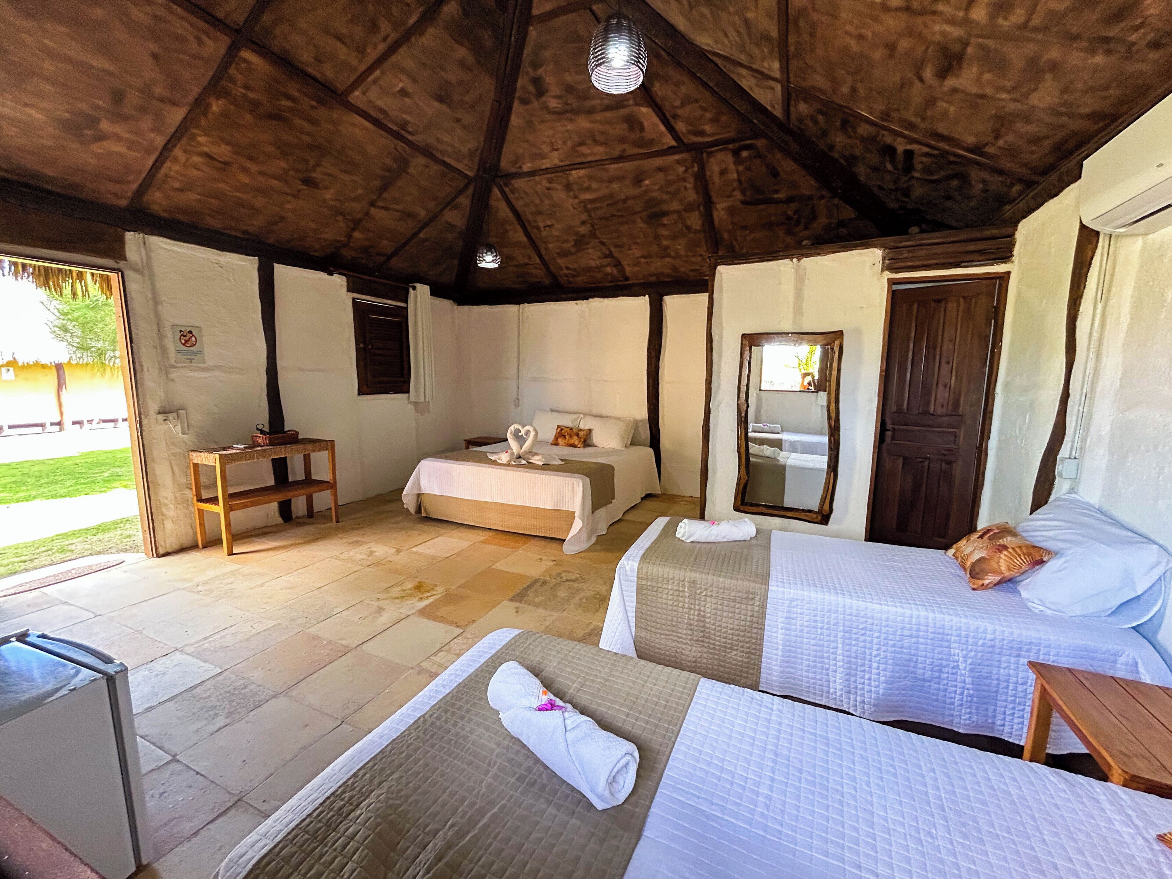 Een kamer met twee bedden, een houten bankje, een tafeltje en een spiegel.