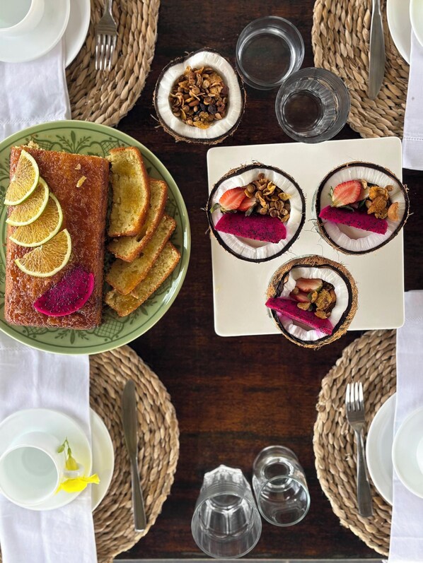 A dining table with a plate of bread, a plate of fruit, and a plate of nuts.