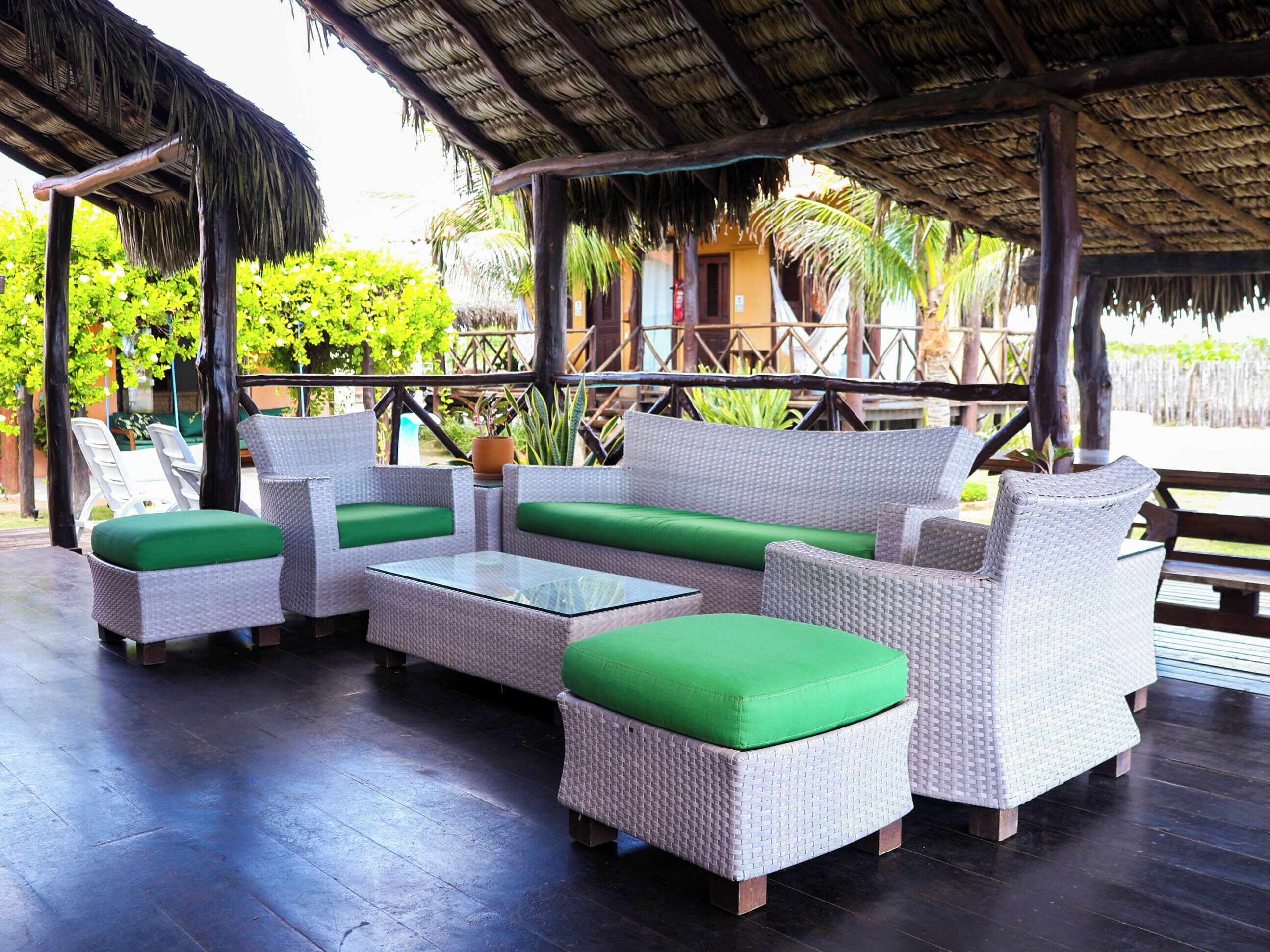 A covered outdoor seating area with wicker furniture and a glass table.