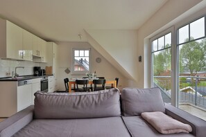 A modern apartment with a kitchenette, dining area, and a large window with a view. - Nice quiet apartment over 2 floors with 2 bedrooms, ideal for the family (Ostseebad Nienhagen)