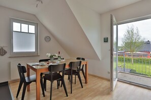 A dining area with a table, chairs, a clock, and a view of the outside. - Nice quiet apartment over 2 floors with 2 bedrooms, ideal for the family (Ostseebad Nienhagen)
