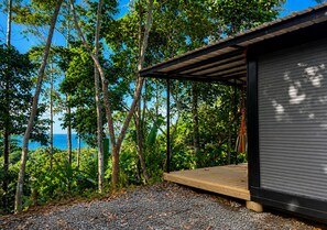 A covered wooden deck with a view of the ocean, surrounded by trees and vegetation. - ArcaVida # 1 Jungle Container • Near Beach (Limon)