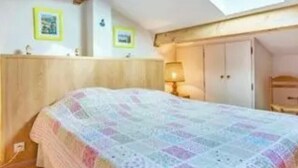 Ein Schlafzimmer mit Bett, Nachttisch, Lampe, Kleiderschrank und Dachfenster.