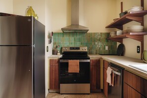 Une cuisine compacte équipée d’un réfrigérateur en acier inoxydable, d’un four encastré et d’une cuisinière.