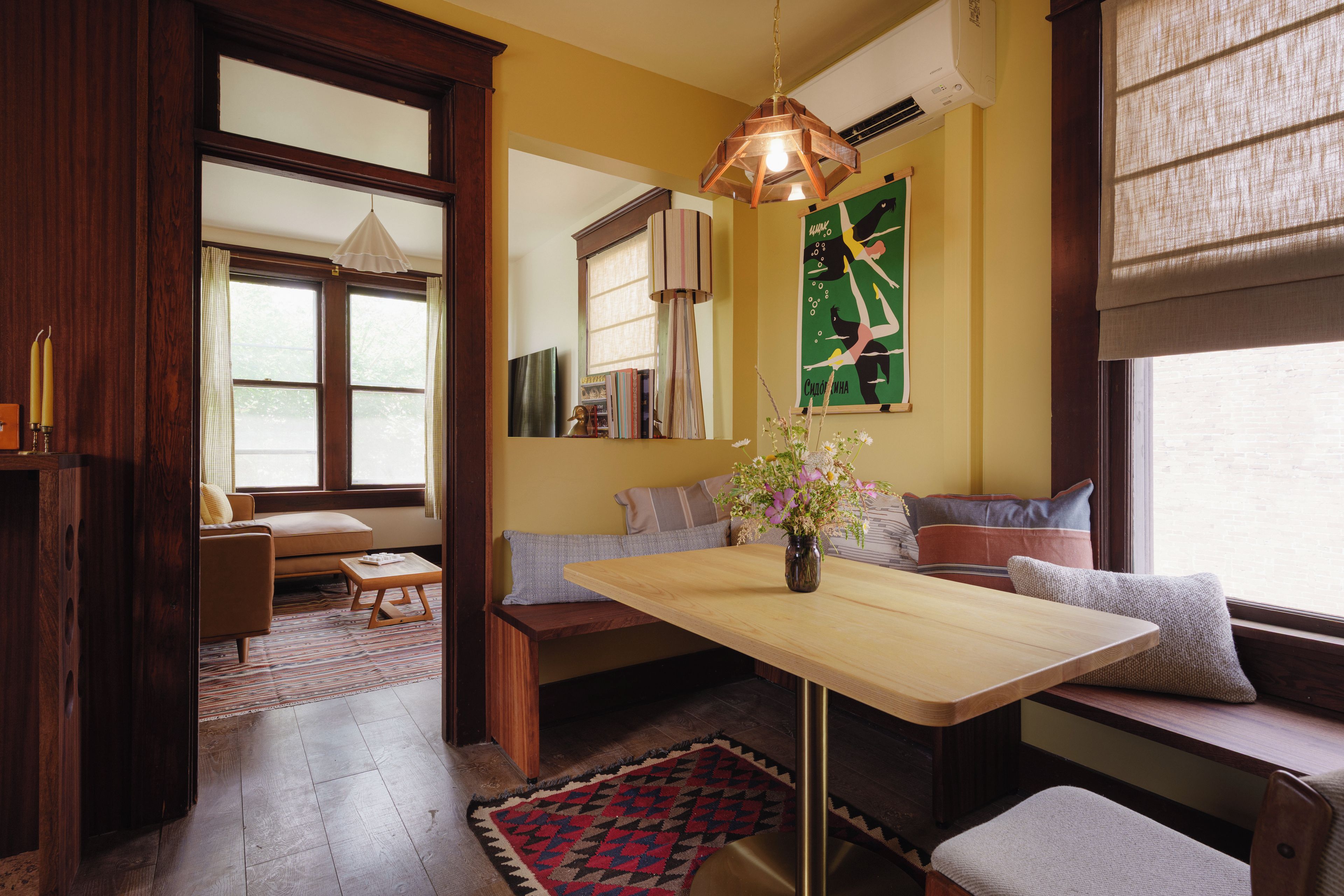 A cozy room with a wooden table, a bench, and a window with curtains.