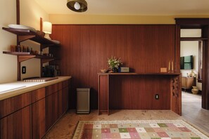 Une cuisine compacte avec des meubles de rangement en bois, un plan de travail, un évier et une petite poubelle.