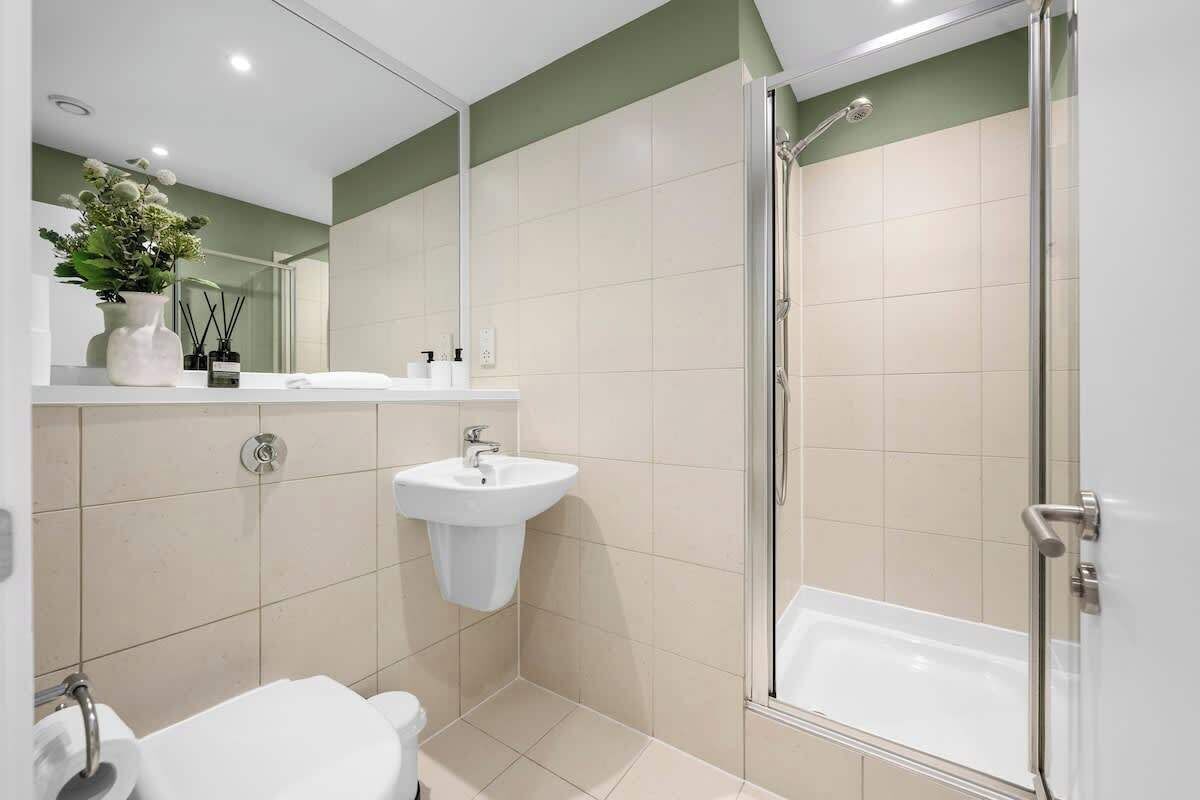 A modern bathroom with a shower, sink, and toilet.