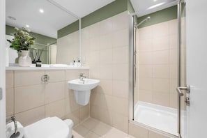 A modern bathroom with a shower, sink, and toilet.