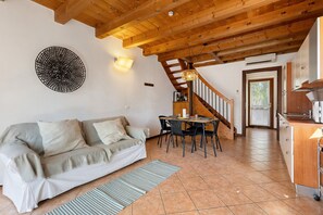 Ein gemütlicher Wohnbereich mit Sofa, Esstisch und Treppe, die zur Küche führt.