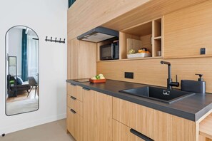 Eine moderne Küche mit Holzausstattung, einer schwarzen Arbeitsplatte, einer eingebauten Mikrowelle und einem Spülbecken.