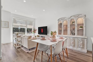 A modern living room with a dining area, a TV, and a decorative cabinet. - Central 3BR Townhome | Near WEM | Family Friendly (Edmonton)