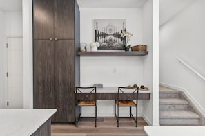 Une cuisine moderne avec des meubles en bois foncé, un plan de travail blanc et deux chaises.
