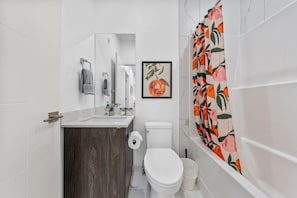 A bathroom with a toilet, sink, mirror, and shower curtain. - Central 3BR Townhome | Near WEM | Family Friendly (Edmonton)