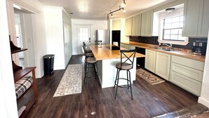 Une cuisine spacieuse dotée d’un îlot central, de meubles de couleur claire et d’un plancher en bois foncé.