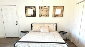 Un lit avec un cadre en métal, deux tables de chevet et trois cadres photo fixés au mur.