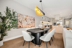 A modern kitchen with a central island, white cabinetry, and a pendant light. - Riverfront HotTub|7 min to Stamp|3 King Bd|Game RM (Calgary)