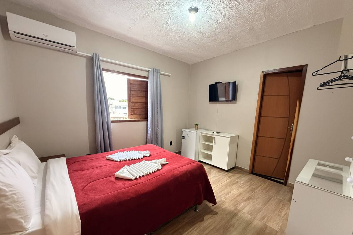 Un dormitorio con cama, escritorio, armario y aire acondicionado.