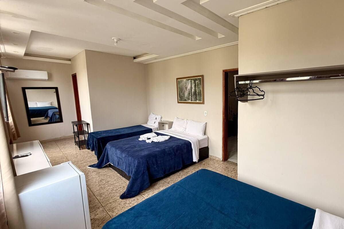 Habitación de hotel con dos camas, un escritorio, un espejo y un cuadro en la pared.