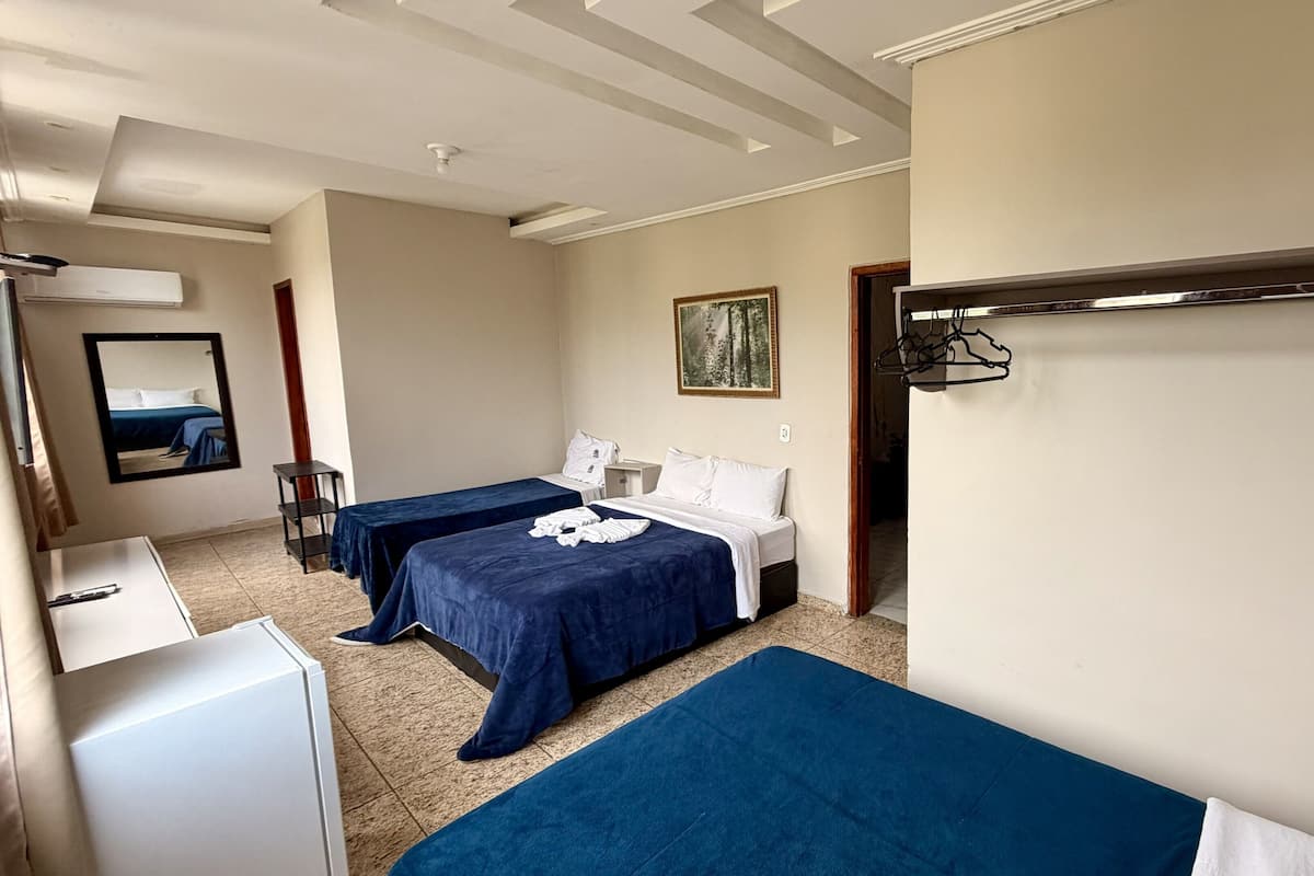 Habitación de hotel con dos camas, un escritorio, un espejo y un cuadro en la pared.