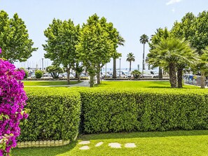 A well-maintained garden with manicured hedges, a variety of trees, and a clear view of the marina in the background. - La Caracola by Interhome (Marina di Andora)