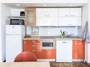 A compact kitchen with white and orange cabinets, a microwave, a toaster, and a dishwasher. - La Caracola by Interhome (Marina di Andora)