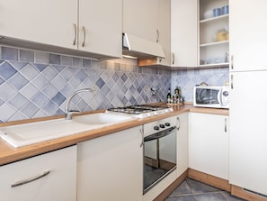 Eine moderne Küche mit Gasherd, Backofen, Spüle und Mikrowelle.