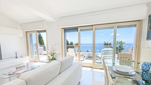 Ein modernes Wohnzimmer mit einer Couch, einem Glastisch und einem Balkon mit Meerblick.