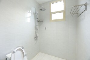 A bathroom with a toilet, a shower, and a window. - khayal suites (Riyadh)