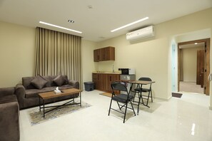 A modern living room with a sofa, coffee table, and dining area. - khayal suites (Riyadh)