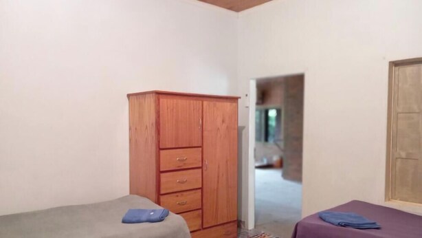 Ein Zimmer mit Holzschrank, Bett und einem kleinen Tisch mit lila Tuch.