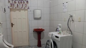 Ein Badezimmer mit Toilette, Waschbecken, Spiegel und Waschmaschine.