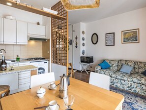 Eine moderne Küche mit Herd, Spüle und einem Essbereich mit Tisch für zwei Personen.